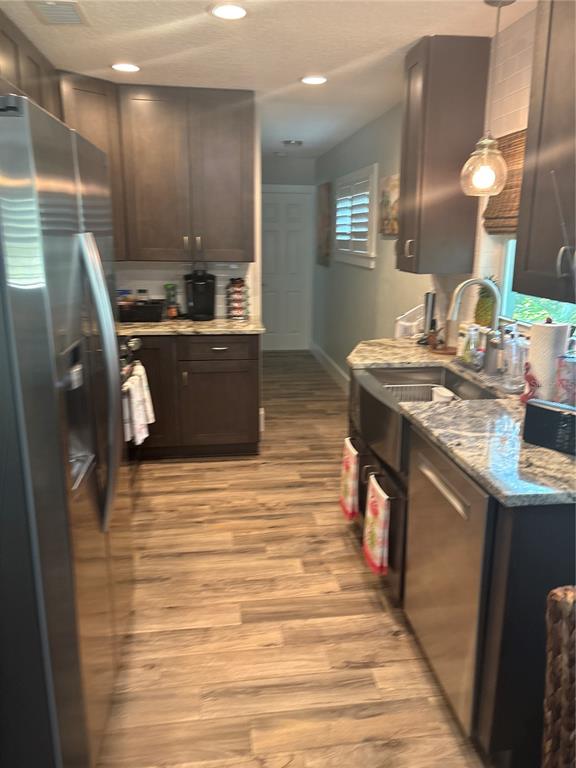 A galley kitchen features dark wood cabinets, granite countertops, stainless steel appliances, and wood-look flooring — 1517 S CENTRAL AVENUE, FLAGLER BEACH, FL