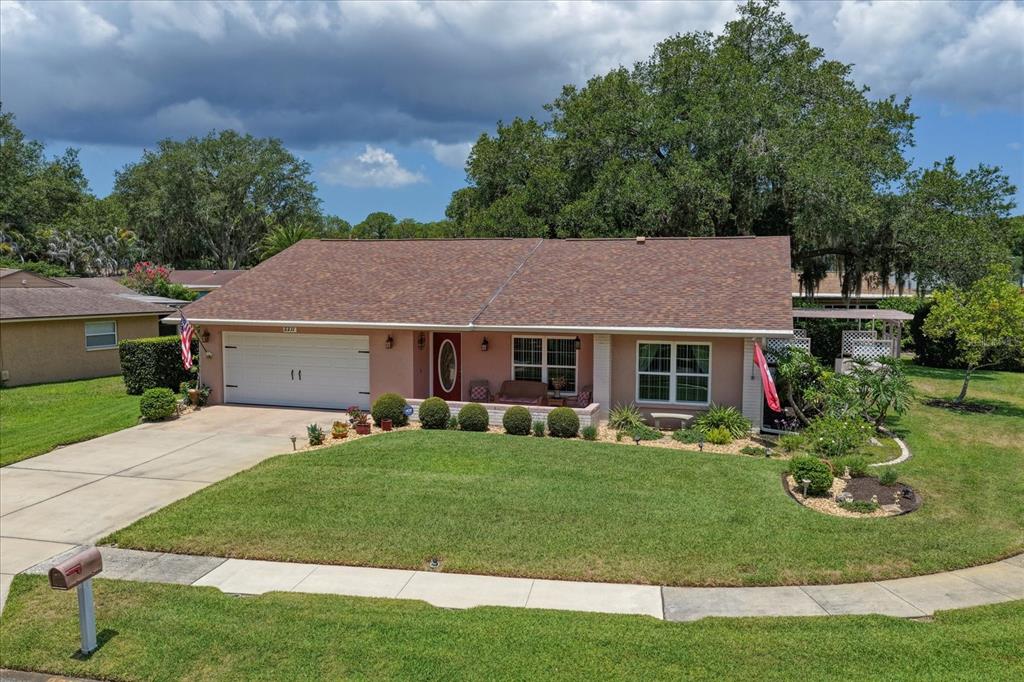 A single-story house with a pink exterior, a two-car garage, and a manicured front lawn — 2211 PORTSIDE PASSAGE, PALM HARBOR, FL
