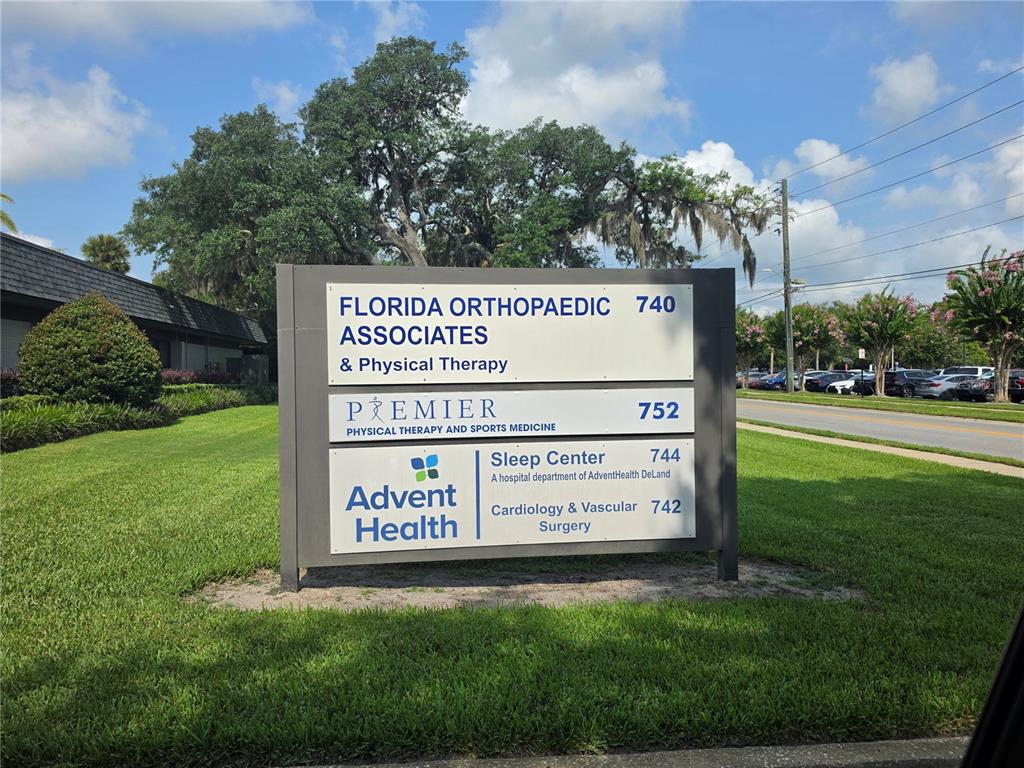 A sign displays the names and addresses of several medical offices on a grassy lawn — 0 WEST PLYMOUTH AVENUE, DELAND, FL