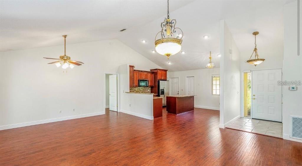 An open-concept living area features vaulted ceilings, wood-look flooring, and a kitchen with dark cabinetry — 957 SOUTHRIDGE TRAIL, ALTAMONTE SPRINGS, FL