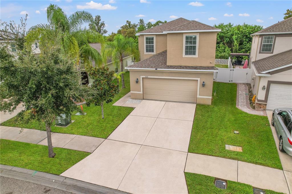 A two-story suburban house with a tan stucco exterior, a two-car garage, and a driveway — 1964 HAWKS VIEW DRIVE, RUSKIN, FL