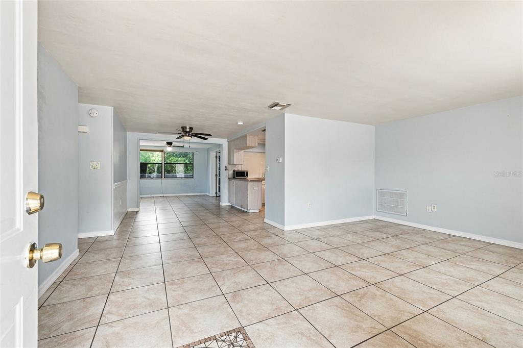 An open-concept living and dining area features light blue walls and beige tile flooring — 3431 OVERLAND DRIVE, HOLIDAY, FL