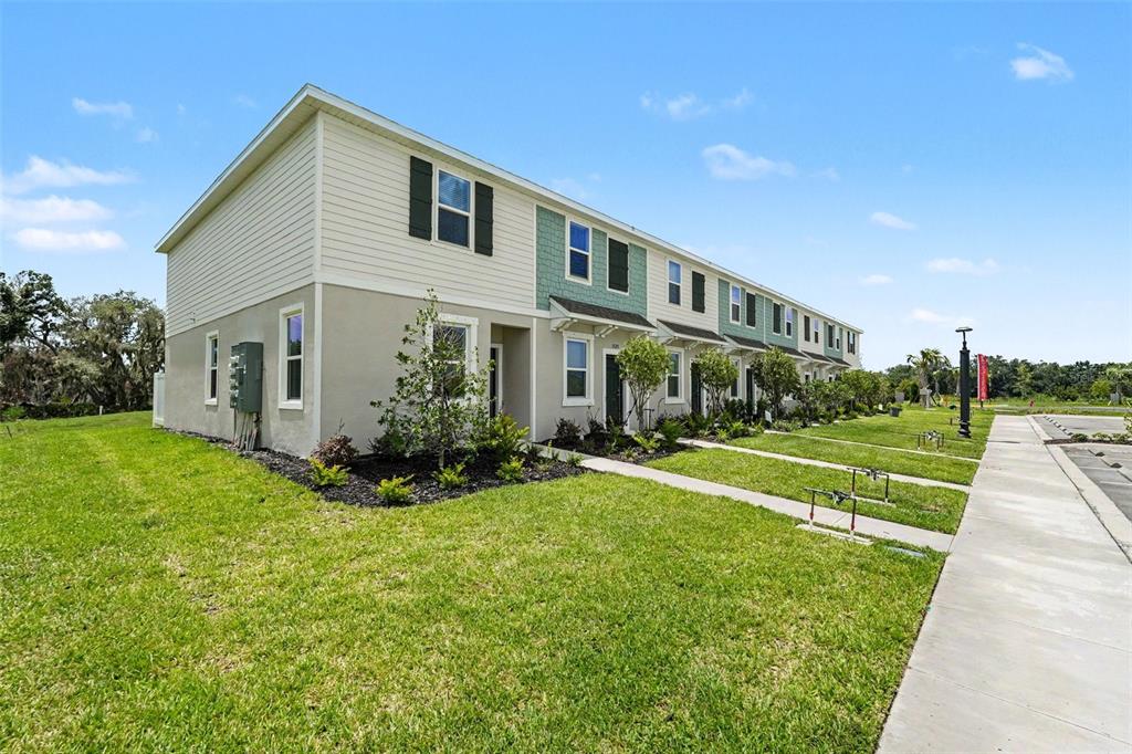 A row of two-story townhomes features light-colored siding, green accents, and a sidewalk — 13207 FORGE AVENUE, PARRISH, FL