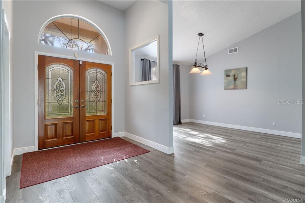 An entryway with wood-look flooring leads into a living area with high ceilings and curtains — 270 N GRANDVIEW AVENUE, HERNANDO, FL