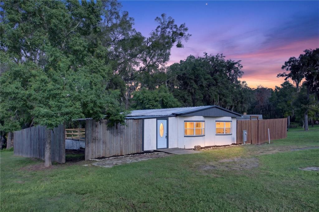 A grassy lot features a stone path leading toward trees under a cloudy blue sky — 6287 MAGNOLIA STREET, KEYSTONE HEIGHTS, FL