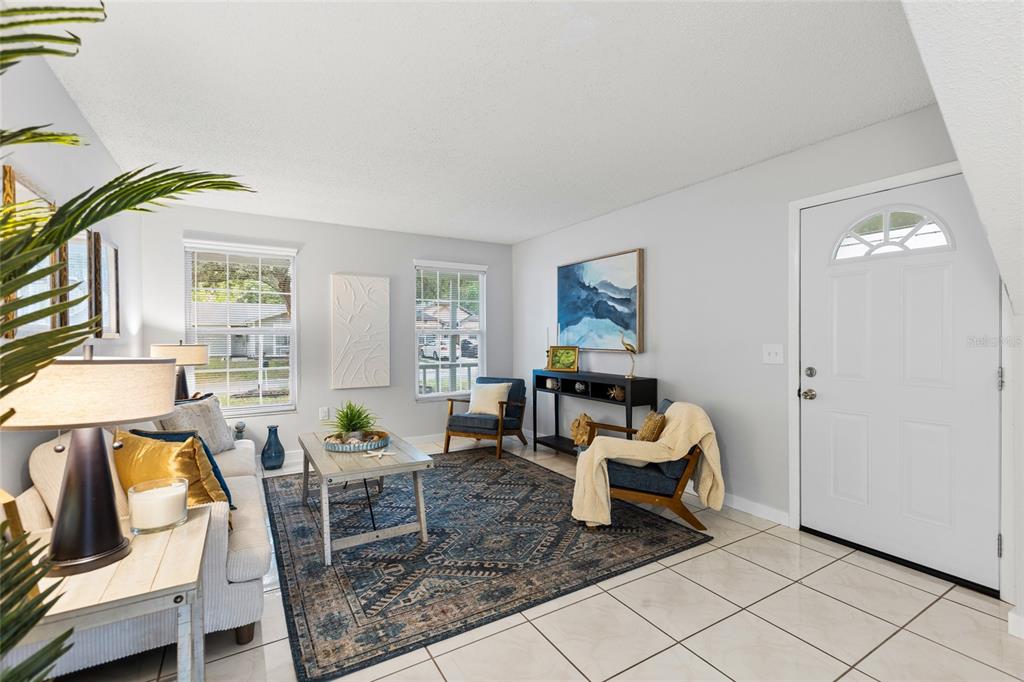 A living room features tile floors, a patterned area rug, two windows, and a front door — 7608 WILLOW PARK DRIVE, TEMPLE TERRACE, FL