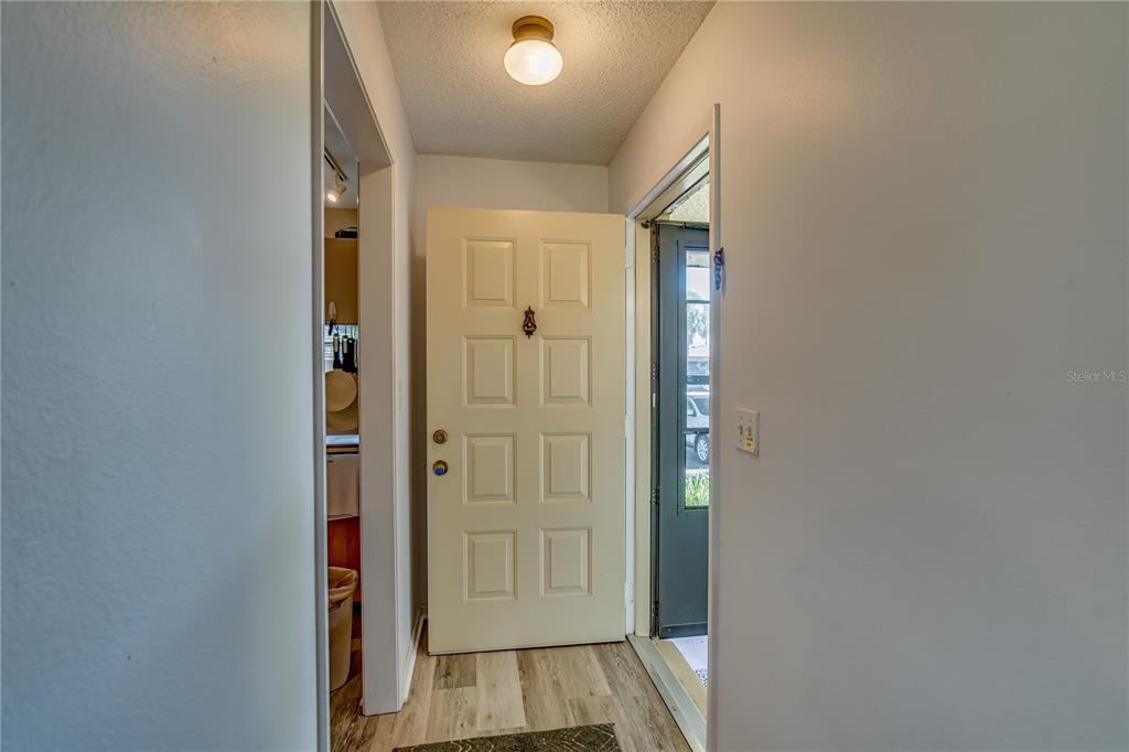 A light-colored front door opens into a small entryway with wood-look flooring and a ceiling light — 1119 9TH CIRCLE SE UNIT 1119, LARGO, FL