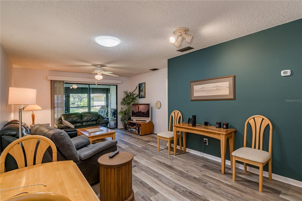 A living room with wood-look flooring, a teal accent wall, and a sliding glass door — 1119 9TH CIRCLE SE UNIT 1119, LARGO, FL