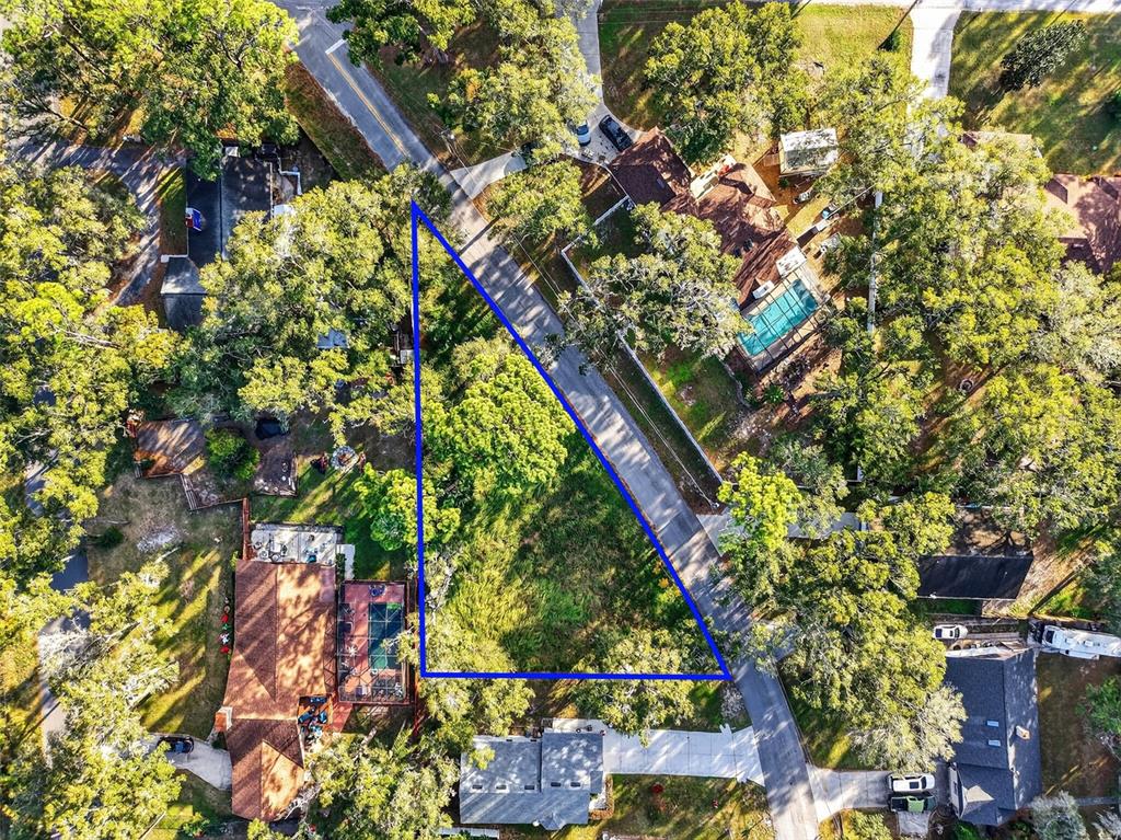 An aerial view shows a triangular vacant lot bordered by roads and surrounding residential houses — APAWAMIS DRIVE, SORRENTO, FL