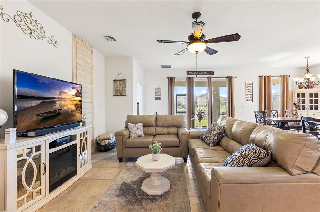 A living room features a television, leather sofas, a ceiling fan, and tile flooring — 5025 JACKEL CHASE DRIVE, WIMAUMA, FL