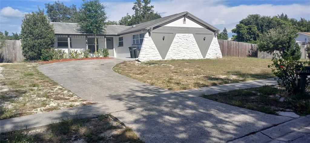 An open-concept living and dining area features tile flooring, gray walls, and a kitchen pass-through — 1019 PENINSULA ROAD, TARPON SPRINGS, FL