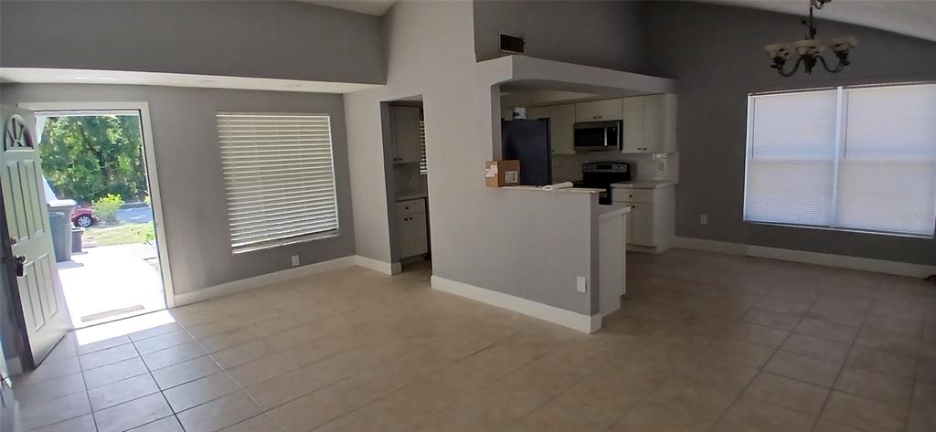 This virtually staged living room features a sectional sofa, two armchairs, and a vaulted ceiling — 1019 PENINSULA ROAD, TARPON SPRINGS, FL