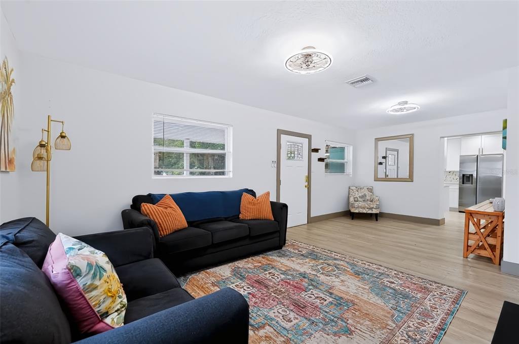 A light green house features a paved front patio with a covered carport and planter box — 6691 56TH AVENUE N, ST PETERSBURG, FL