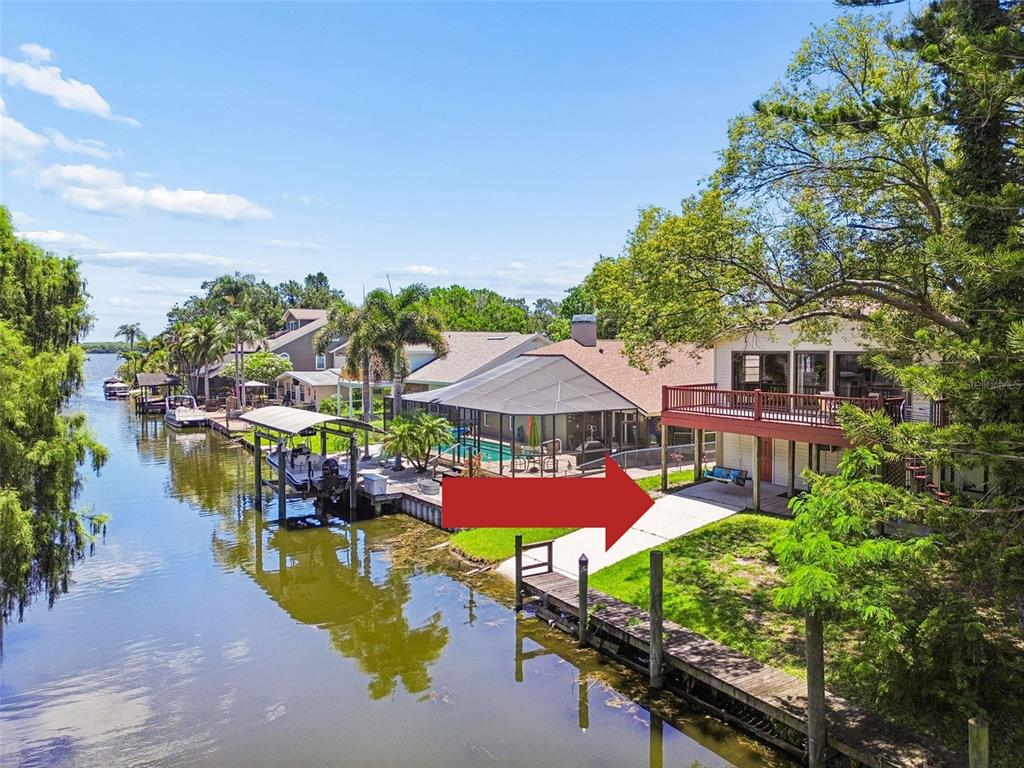 An aerial view shows a residential neighborhood with houses situated along a canal and lake — 3141 N CANAL DRIVE, PALM HARBOR, FL