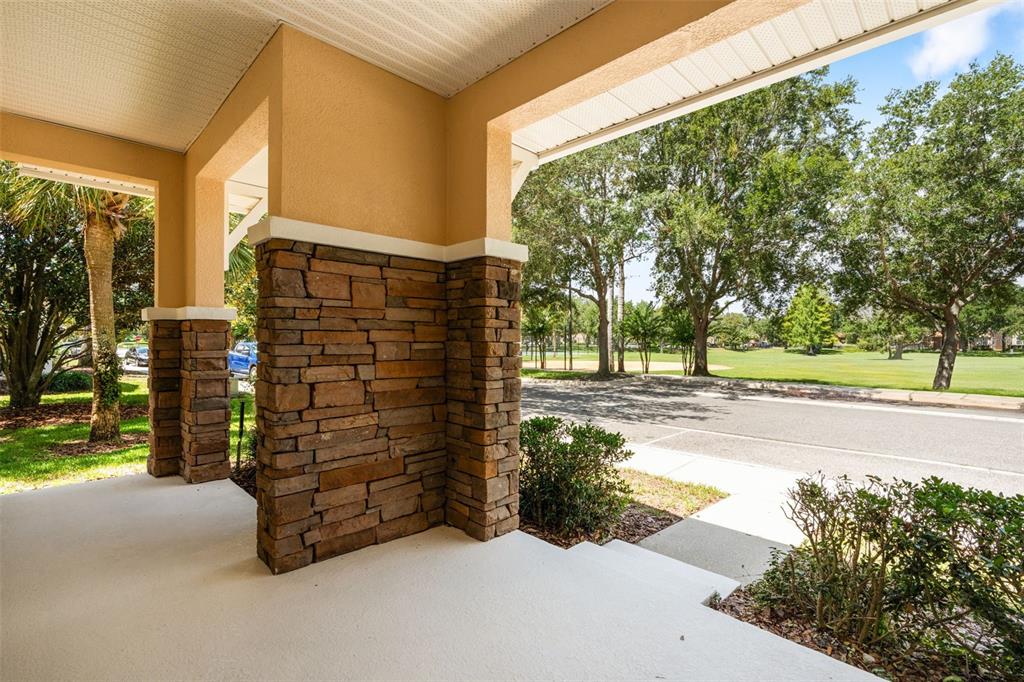 A living room features a stone fireplace, a wall-mounted television, and brown leather furniture — 7327 MILLSTONE STREET, WINDERMERE, FL