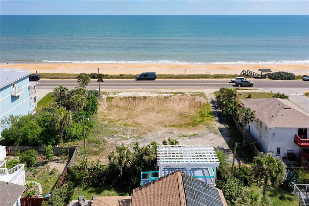 An aerial view shows a vacant, excavated beachside lot situated between two houses and a road — 1005 N OCEAN SHORE BOULEVARD, FLAGLER BEACH, FL