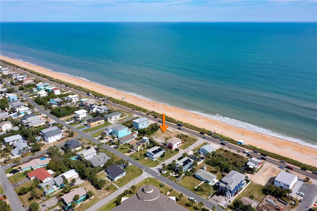 An aerial view shows a coastal neighborhood with an orange arrow pointing to a vacant lot — 1005 N OCEAN SHORE BOULEVARD, FLAGLER BEACH, FL