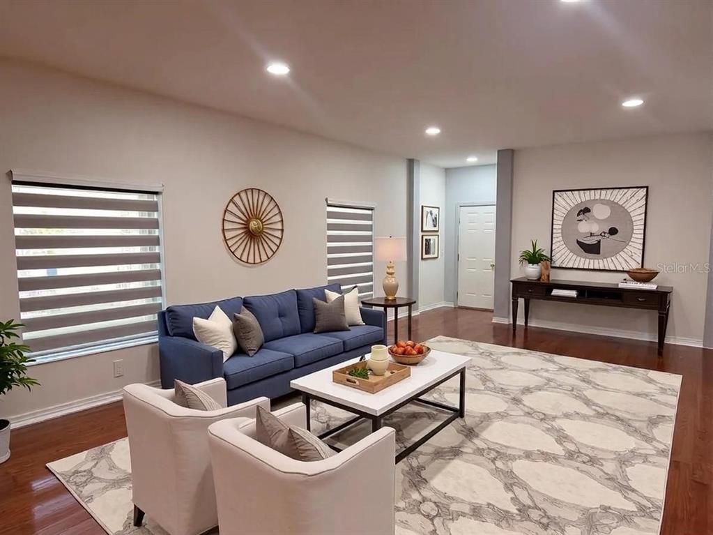 A living room features a blue sofa, two white armchairs, and a patterned area rug — 10245 DEVONSHIRE LAKE DRIVE, TAMPA, FL