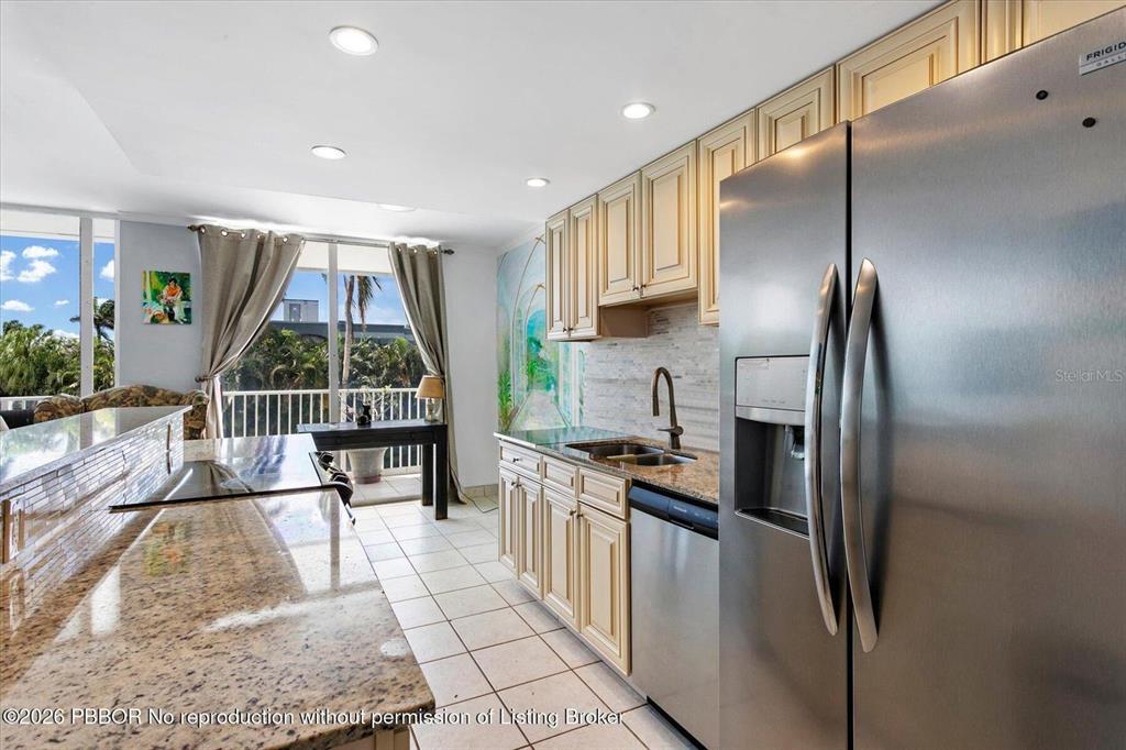 A kitchen features granite countertops, light wood cabinets, stainless steel appliances, and a balcony view — 2860 S OCEAN BOULEVARD UNIT 208, PALM BEACH, FL
