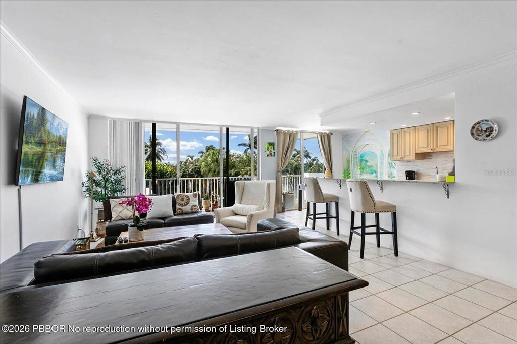 A living room with a dark leather sofa, tile flooring, and an open kitchen breakfast bar — 2860 S OCEAN BOULEVARD UNIT 208, PALM BEACH, FL