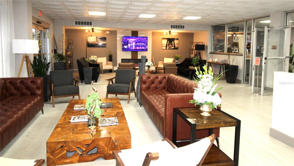 A lobby features brown leather sofas, dark armchairs, a wooden coffee table, and ceiling tiles — 7150 N TAMIAMI TRAIL UNIT C226, SARASOTA, FL