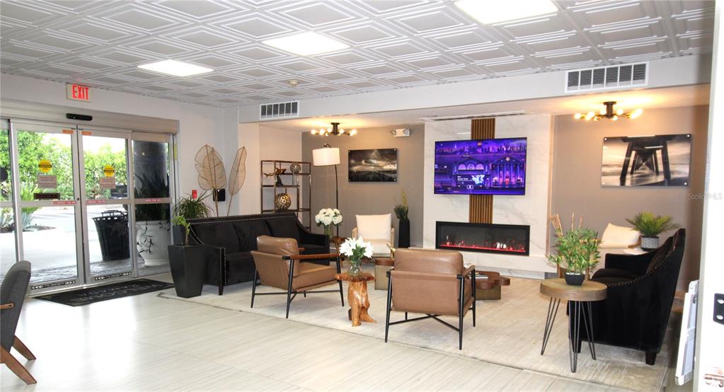 A modern lobby features a fireplace, wall-mounted television, seating area, and a coffered ceiling — 7150 N TAMIAMI TRAIL UNIT C226, SARASOTA, FL