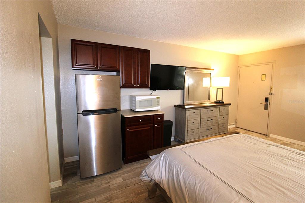 A bedroom features a stainless steel refrigerator, dark wood cabinets, a microwave, and a dresser — 7150 N TAMIAMI TRAIL UNIT C226, SARASOTA, FL