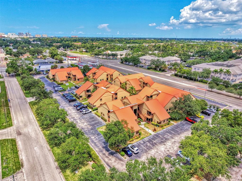 An aerial view of a multi-unit residential complex with orange metal roofs and parking lots — 2831 RINGLING BOULEVARD UNIT E214, SARASOTA, FL