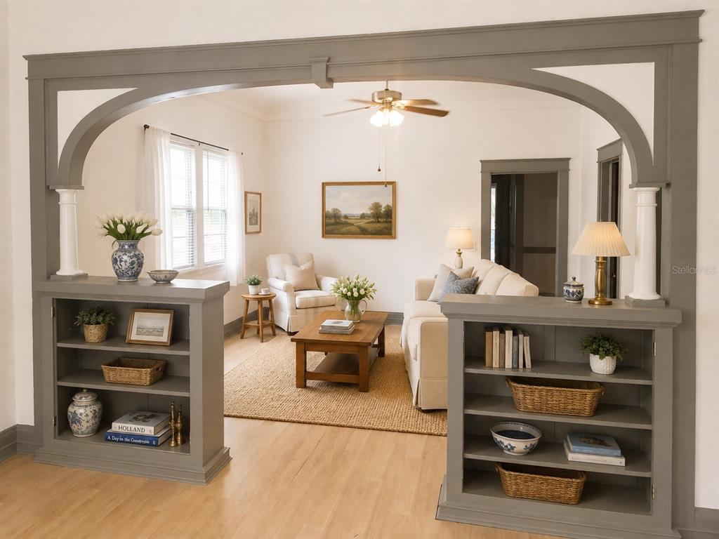 A living room viewed through a wide, gray-painted arched opening with built-in shelving units — 2107 W CHESTNUT STREET, TAMPA, FL