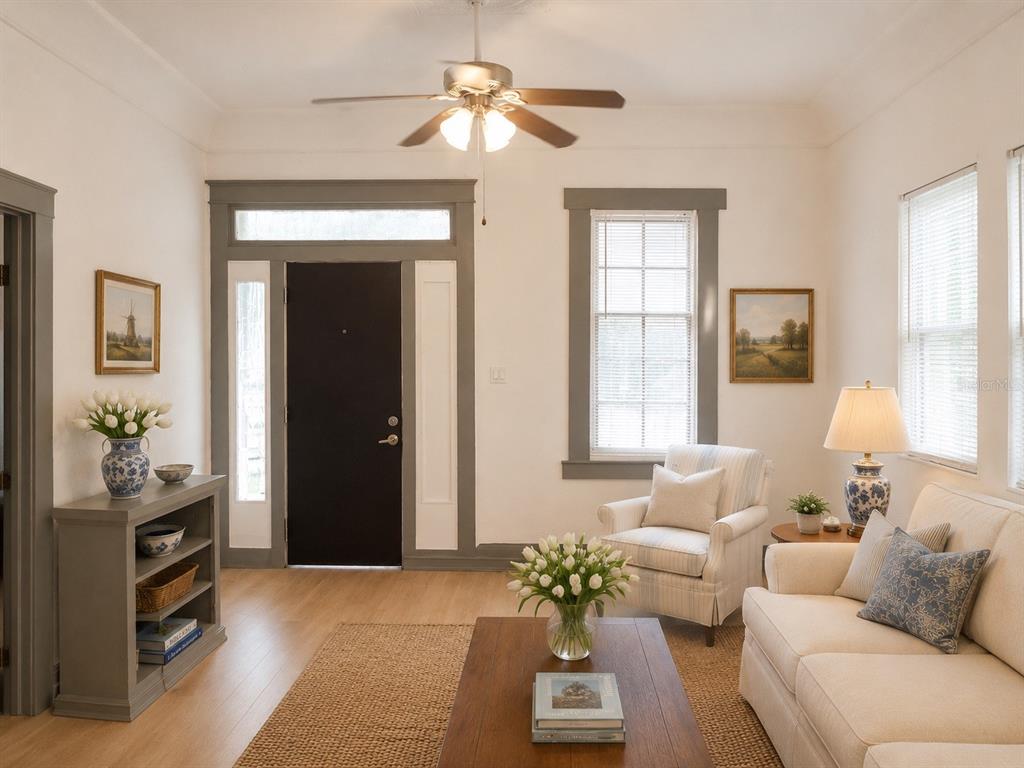 A living room features a dark front door, light wood floors, a sofa, and armchairs — 2107 W CHESTNUT STREET, TAMPA, FL