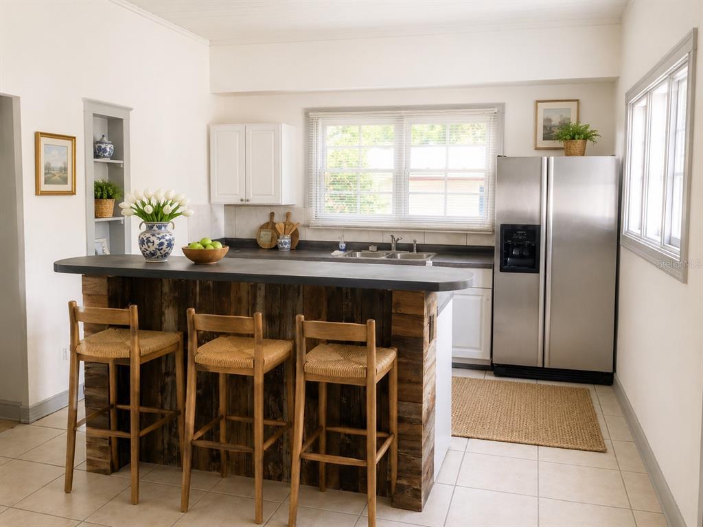 A kitchen features a rustic wood-paneled island with bar stools and stainless steel appliances — 2107 W CHESTNUT STREET, TAMPA, FL