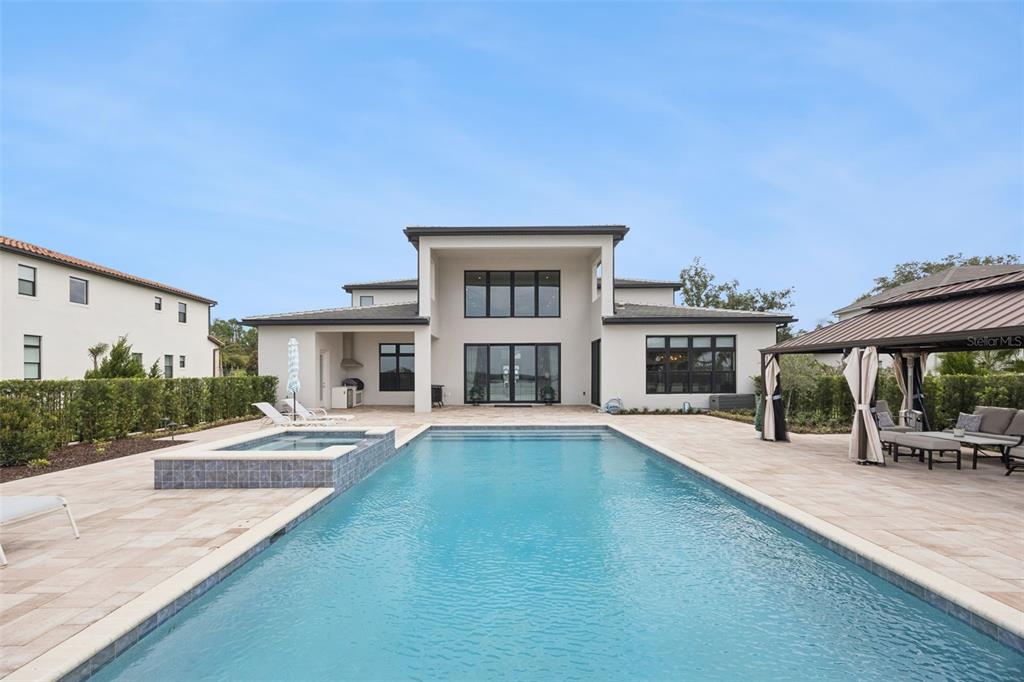 A modern two-story house exterior features a swimming pool, a spa, and a covered patio — 15421 PENDIO DRIVE, MONTVERDE, FL