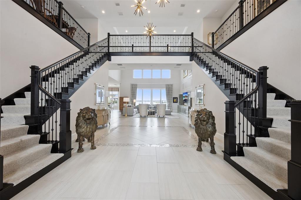 A grand foyer features dual staircases, two lion statues, and a view into the living room — 15421 PENDIO DRIVE, MONTVERDE, FL