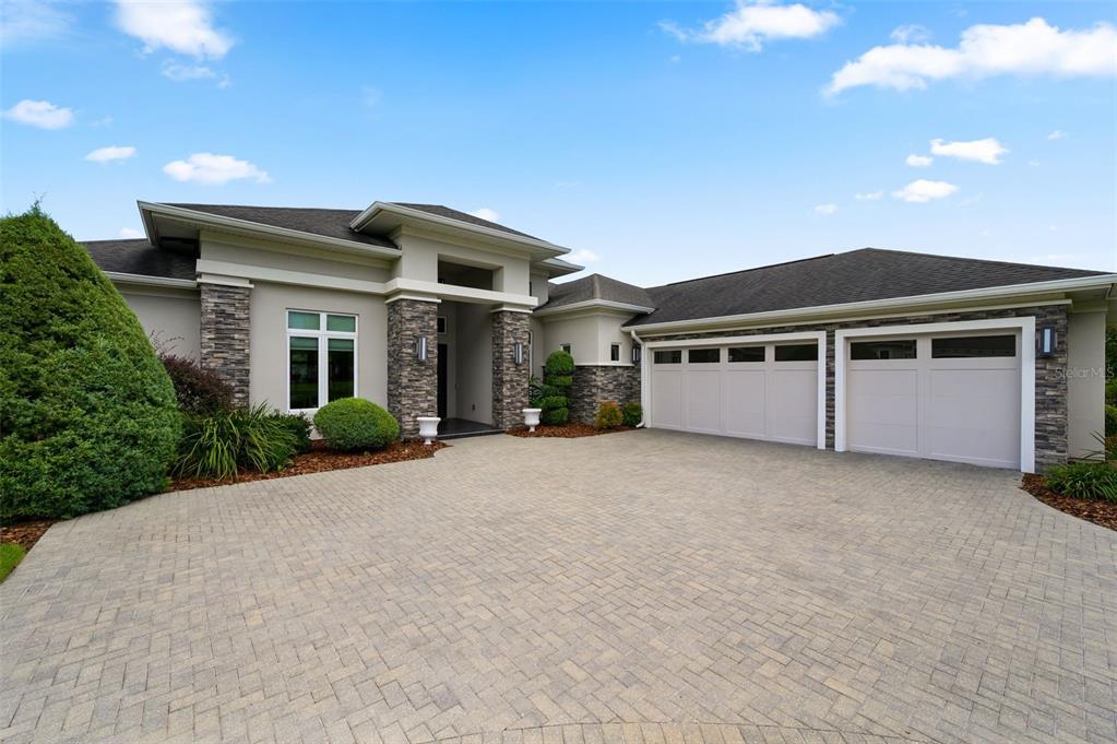 A modern house exterior features a stone-accented facade, a paved driveway, and a three-car garage — 2807 SW 117TH STREET, GAINESVILLE, FL