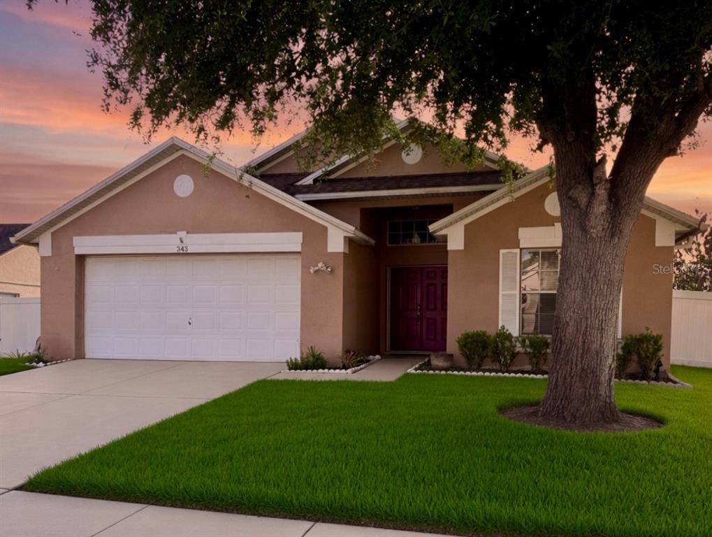 A single-story suburban house with a tan stucco exterior, a two-car garage, and a driveway — 343 LYTTON CIRCLE, ORLANDO, FL
