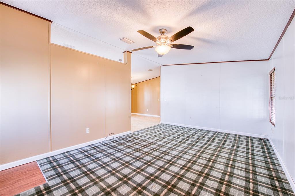 An interior room features plaid carpeting, tan and white paneled walls, and a ceiling fan — 403 BLUE MARLIN DRIVE, OLDSMAR, FL