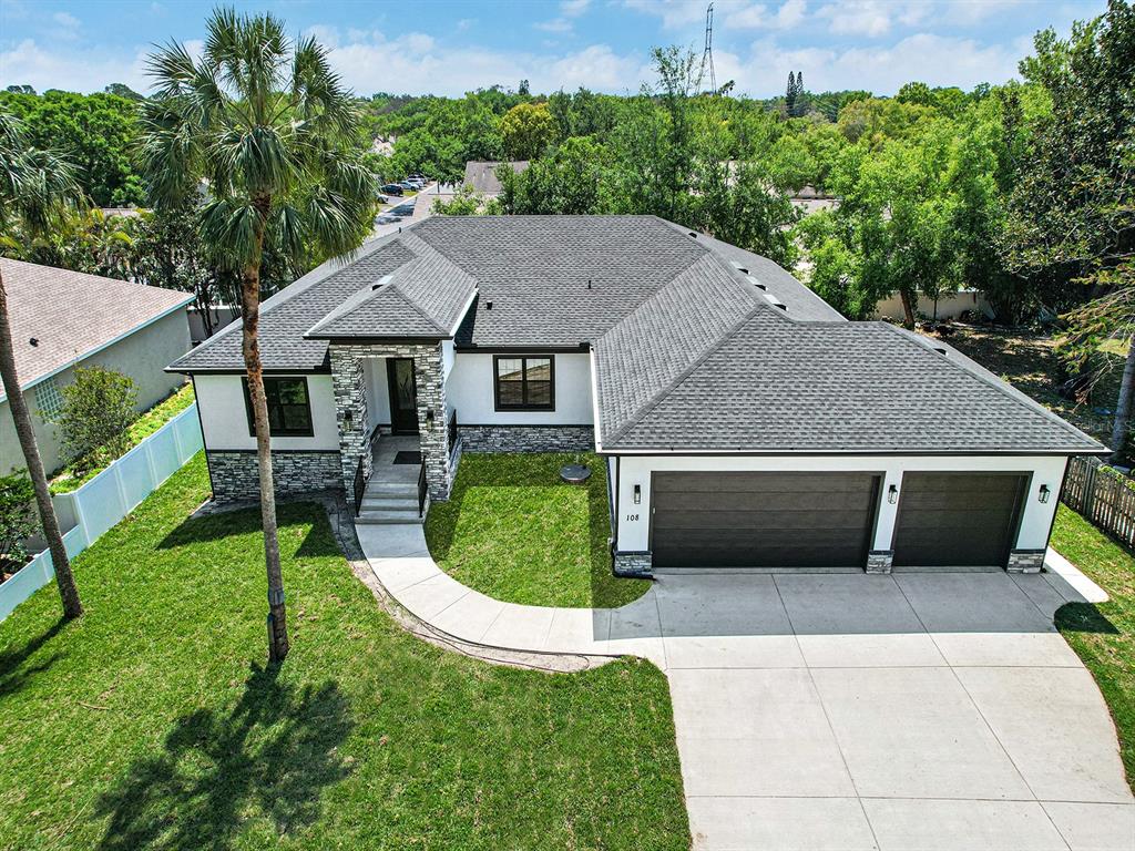 A single-story house with a stone-accented entryway, a three-car garage, and a manicured lawn — 108 IRWIN STREET E, SAFETY HARBOR, FL