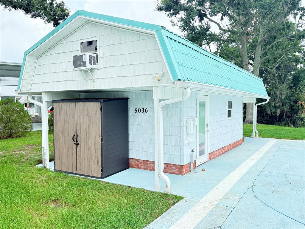 A light blue gambrel-roofed structure features a window air conditioner and an attached storage shed — 5036 SHORE LINE DRIVE, POLK CITY, FL