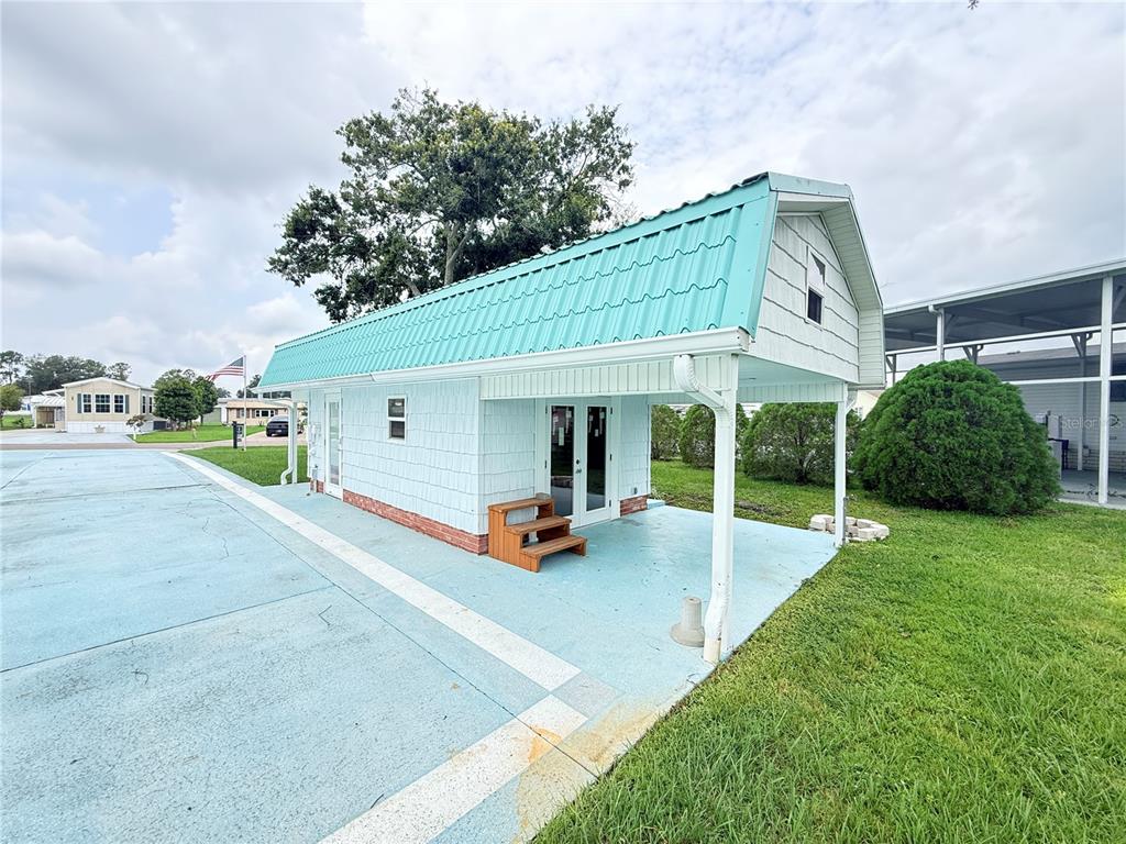 A light blue shed with a teal metal roof sits on a paved lot — 5036 SHORE LINE DRIVE, POLK CITY, FL