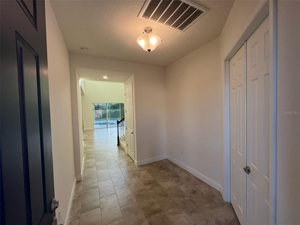 A tiled entryway features a light fixture, a white closet, and a view toward stairs — 8794 CRESCENDO AVENUE, WINDERMERE, FL