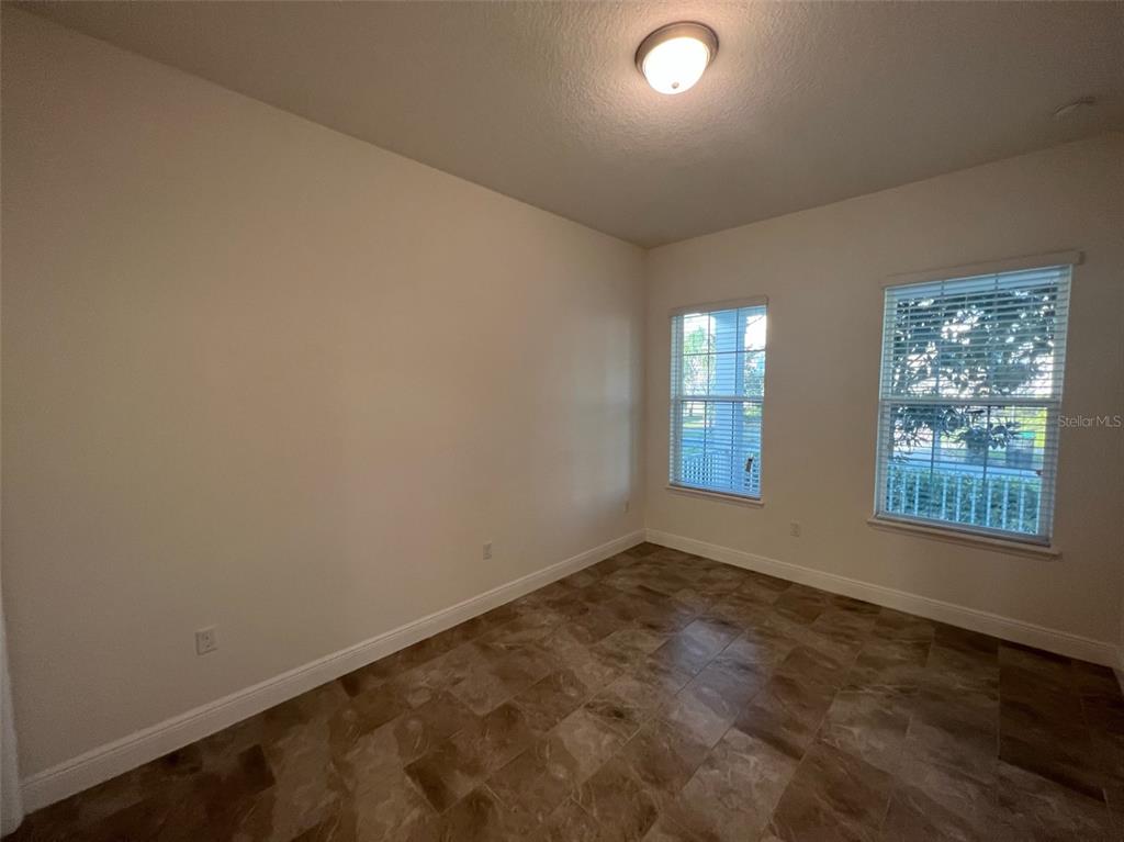An empty room features beige walls, tile flooring, and two windows with white blinds — 8794 CRESCENDO AVENUE, WINDERMERE, FL