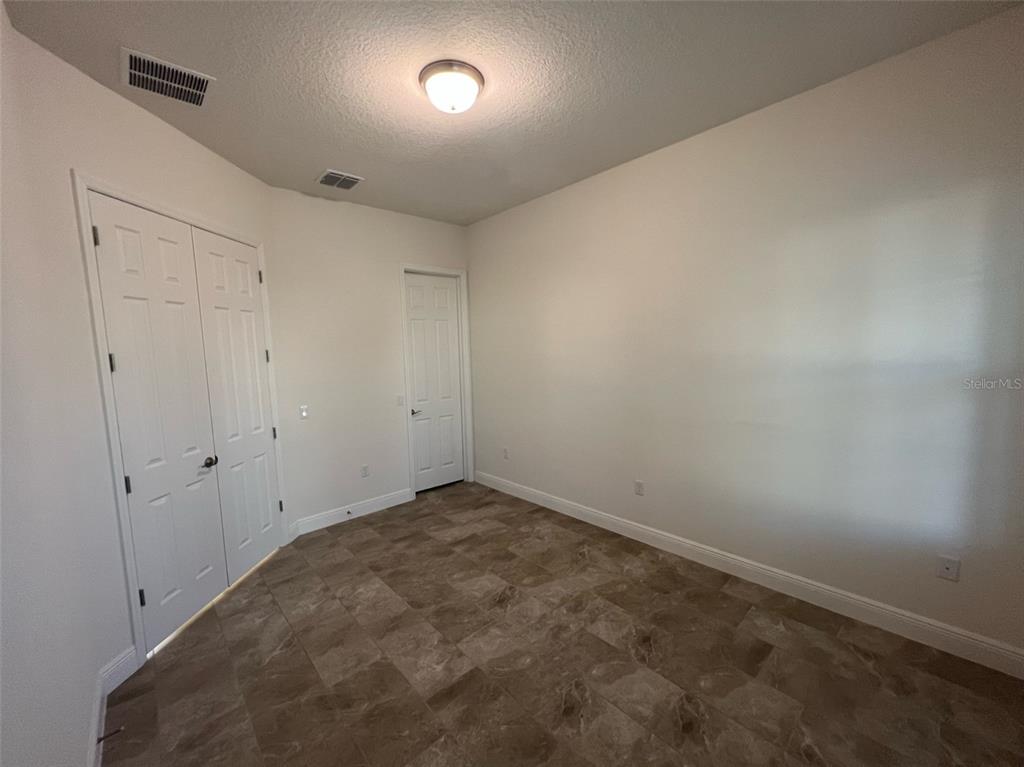 An empty room features white walls, a light fixture, and brown tile flooring — 8794 CRESCENDO AVENUE, WINDERMERE, FL