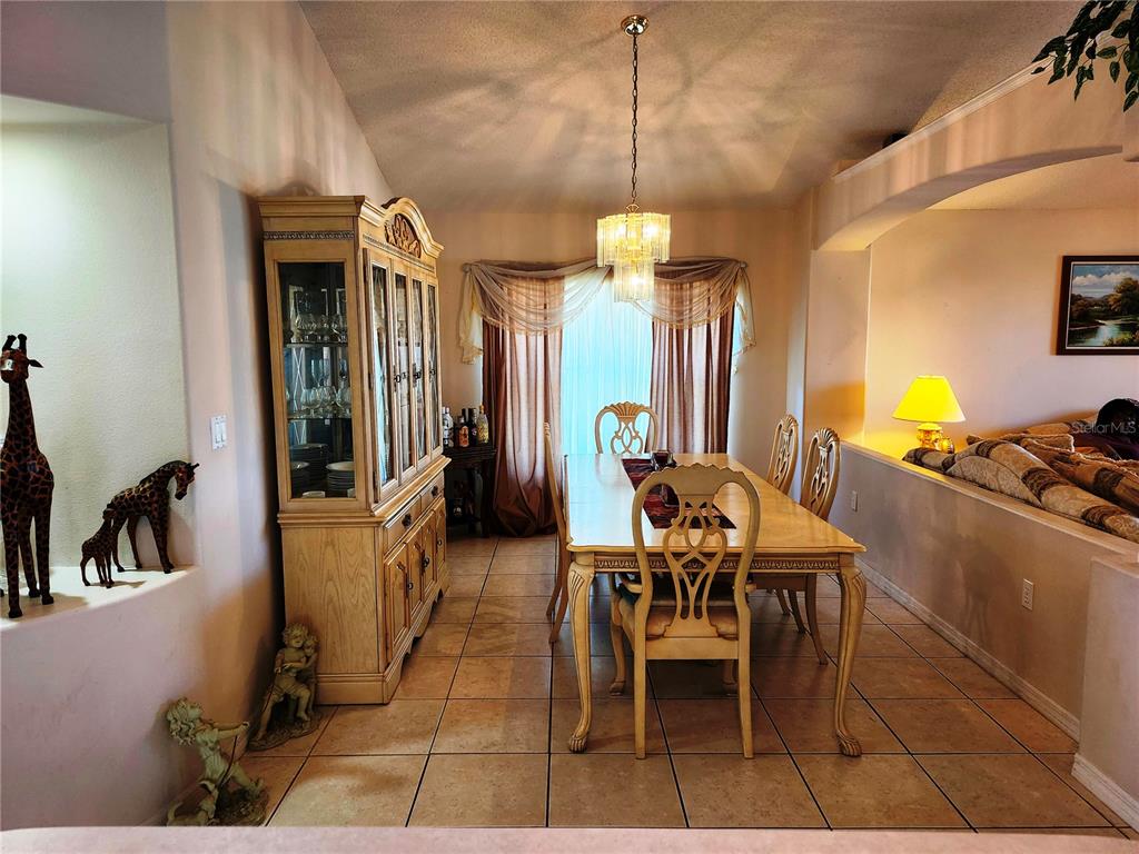A dining room features a wooden hutch, a table with six chairs, and tile flooring — 4613 EAGLET LANE, KISSIMMEE, FL