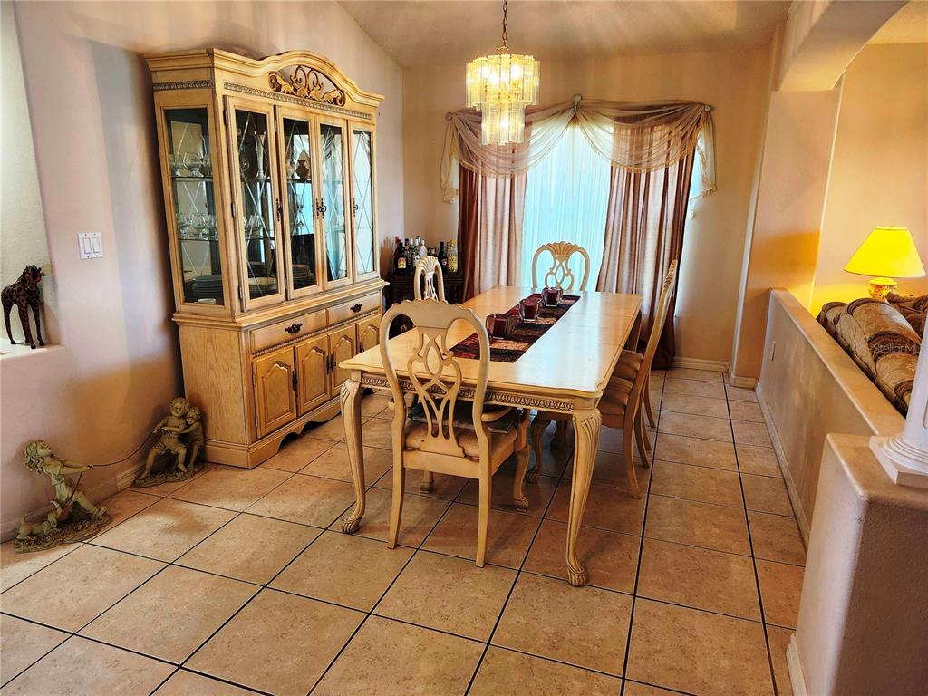 A dining room features a light wood hutch, a matching table with chairs, and tile flooring — 4613 EAGLET LANE, KISSIMMEE, FL