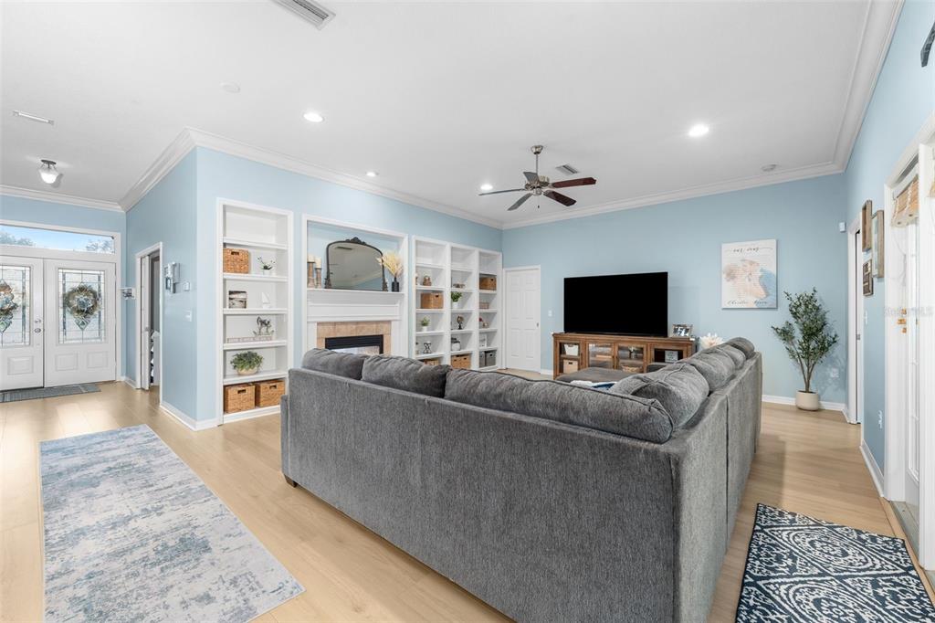 A living room features light blue walls, a gray sectional sofa, built-in shelving, and wood flooring — 6940 SW 86TH TERRACE, GAINESVILLE, FL