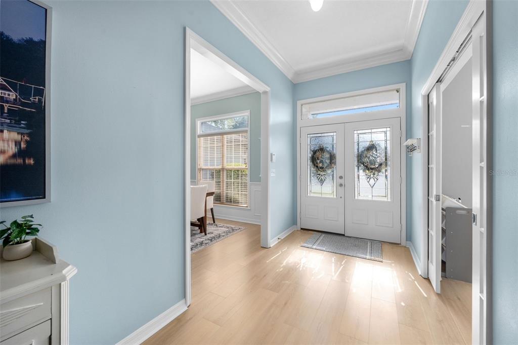 A bright entryway features light blue walls, light wood flooring, and a double front door — 6940 SW 86TH TERRACE, GAINESVILLE, FL