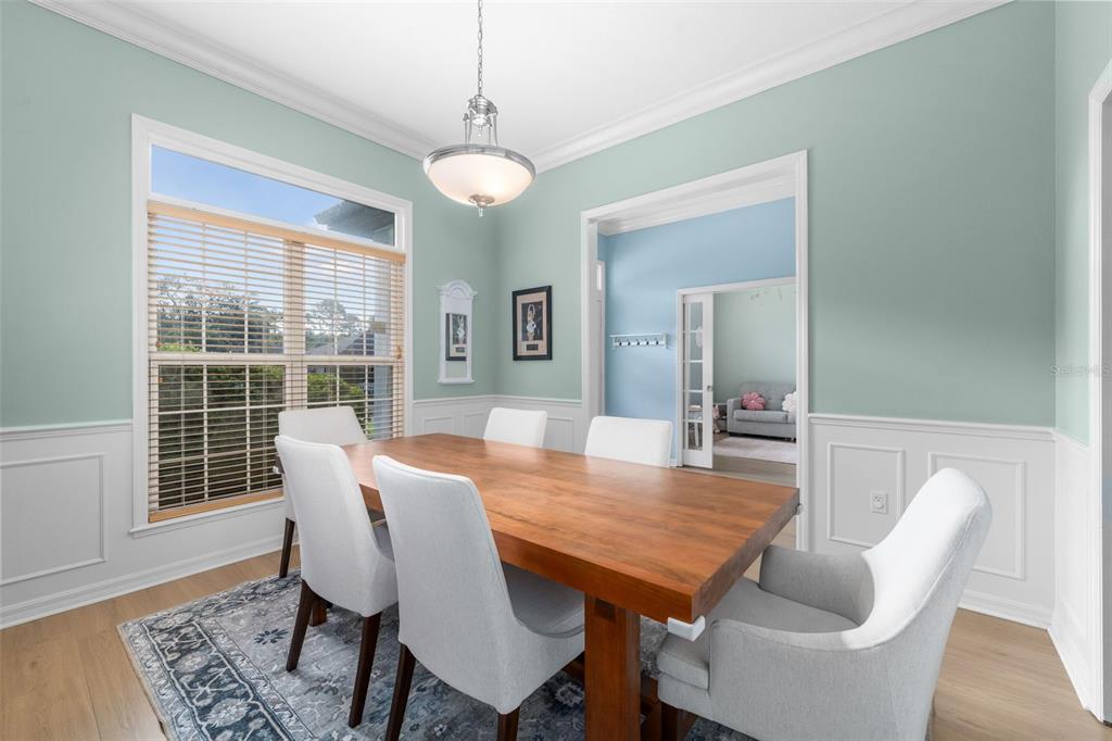 A dining room features a wooden table, six upholstered chairs, a rug, and light blue walls — 6940 SW 86TH TERRACE, GAINESVILLE, FL