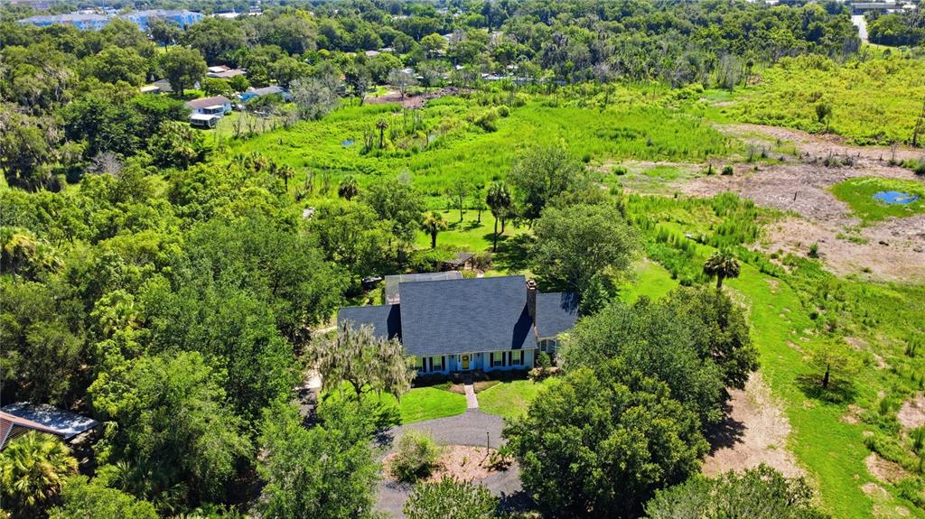 A gray house with a yellow front door sits behind a circular gravel driveway — 1245 WESTOAK DRIVE, DELAND, FL