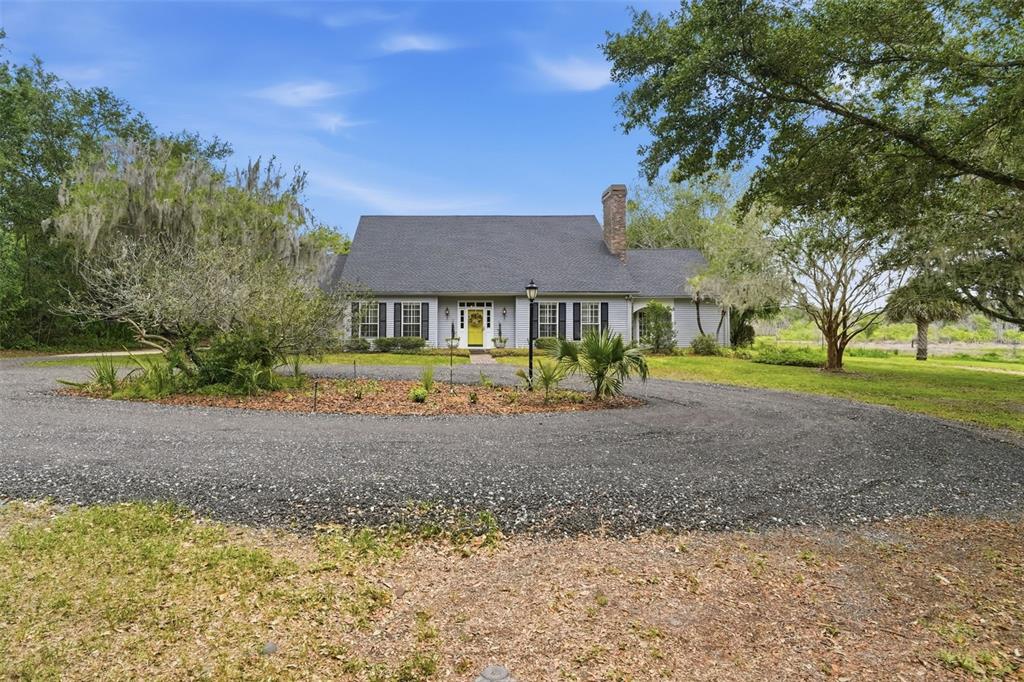 An aerial view shows a house with a dark roof surrounded by trees and grass — 1245 WESTOAK DRIVE, DELAND, FL