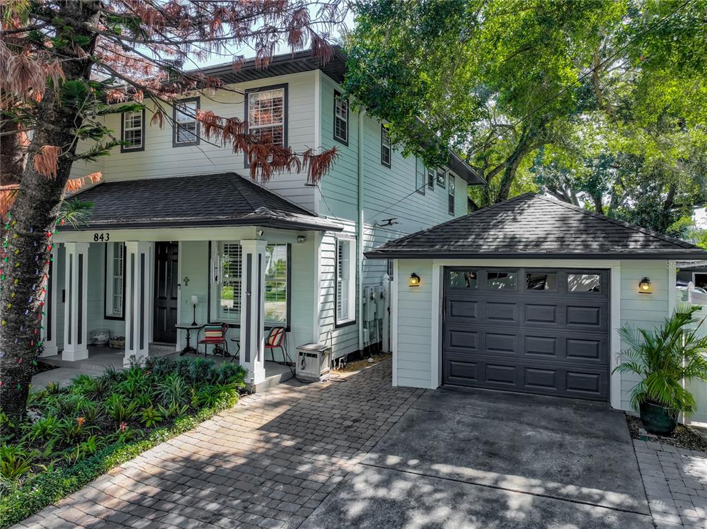 The exterior of a two-story house features a front porch, a tree with string lights, and landscaping — 843 ALTALOMA AVENUE, ORLANDO, FL